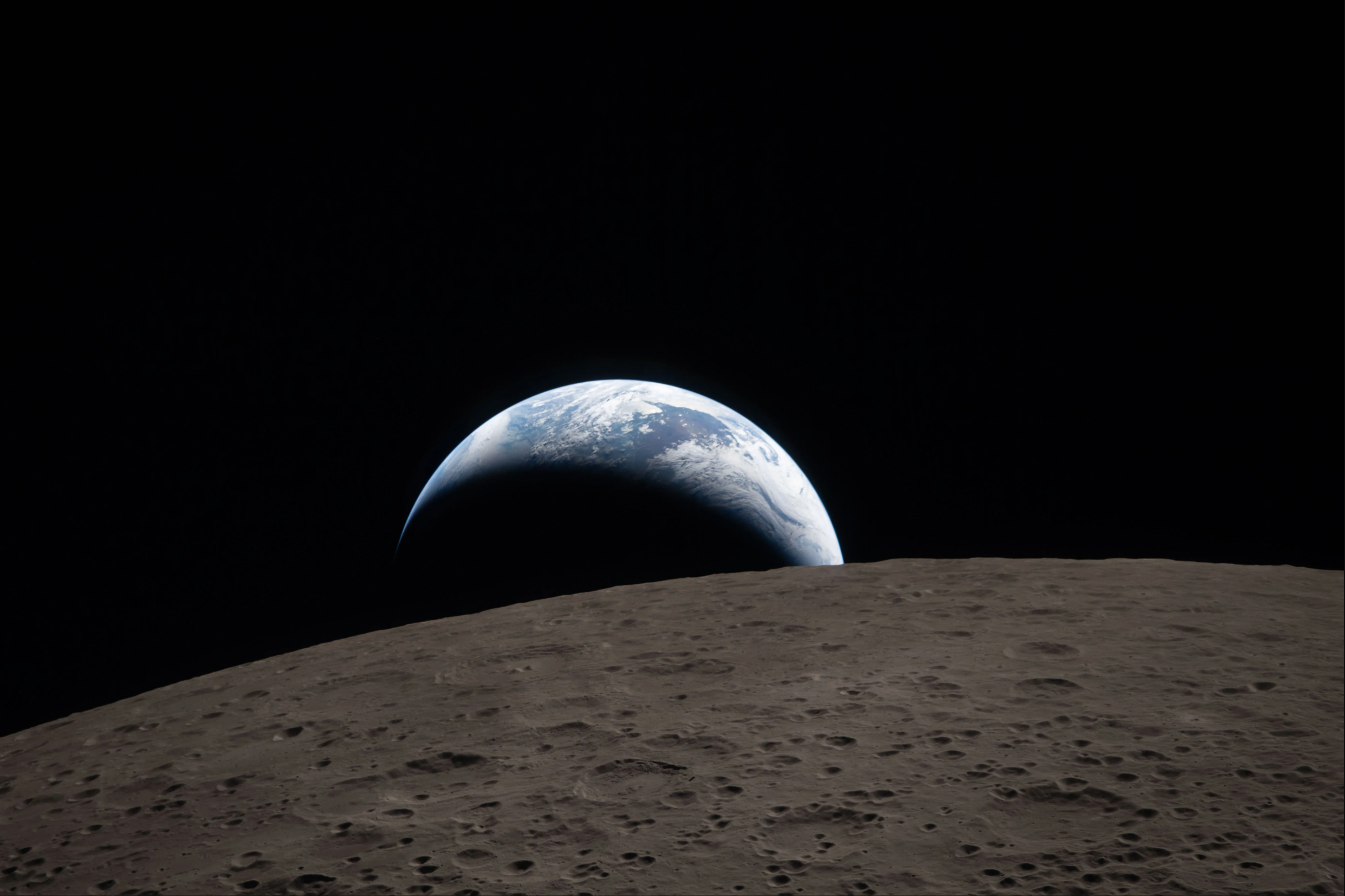 Earth sets over the horizon of the crater-speckled far side of the moon.